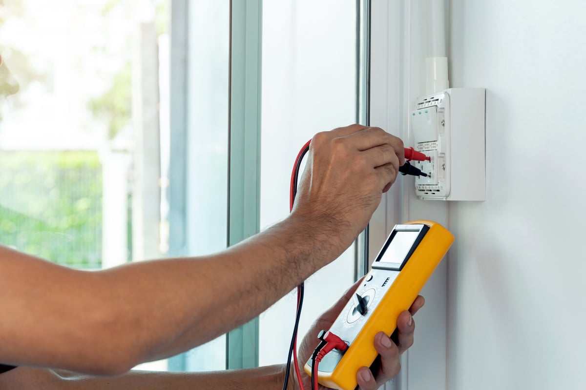 Electrician using a digital meter to measure the voltage at