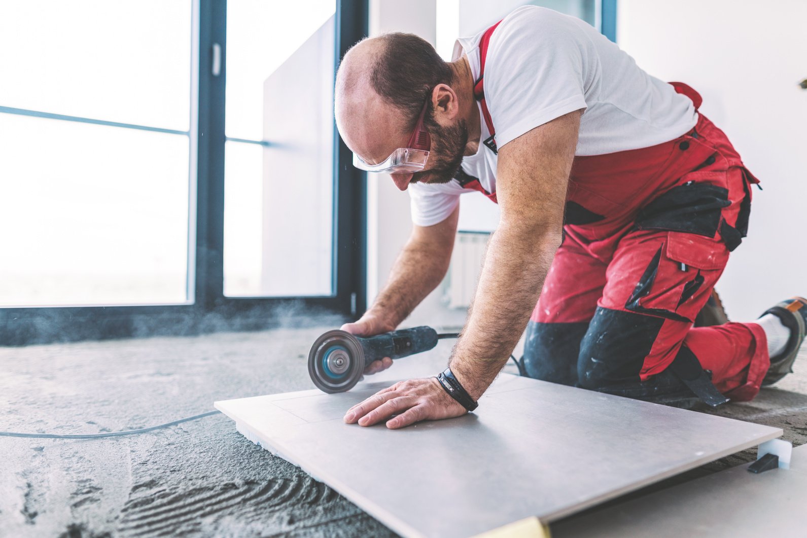 Tile mason cutting square floor tile